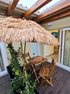 un patio con mesa y sillas bajo una sombrilla de paja en VILLAS com piscina, en Vila Nova de Gaia