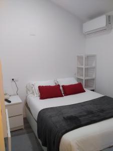 1 dormitorio con 1 cama blanca grande con almohadas rojas en HOMELY Duplex Curtidores, en Cuenca