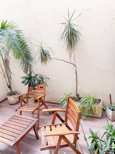 3 sillas de madera en un patio con plantas en Hermoso loft en zona Recoleta c pileta! en Buenos Aires