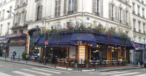 ein Restaurant mit blauer Markise auf einer Stadtstraße in der Unterkunft HAUSSMANN ESPACE in Paris