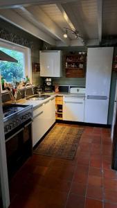 a kitchen with white appliances and a tile floor at comfortable chalet in a unique location in forest in Essen