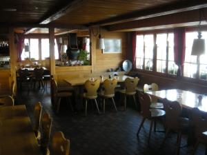 een eetkamer met tafels, stoelen en ramen bij Gasthaus Elsigbach in Achseten