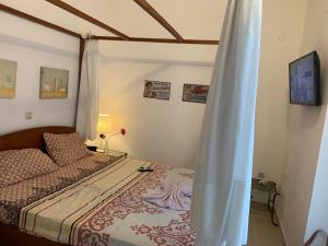 1 dormitorio con cama y cortina en Villa Evita , suites 1, Athytos,63m2,a/c,privacy, en Afitos