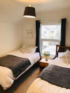 1 dormitorio con 2 camas y ventana en Spacious 3 bed house near beach!, en Lowestoft