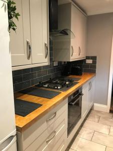 eine Küche mit weißen Schränken und einem Herd mit Backofen in der Unterkunft Spacious 3 bed house near beach! in Lowestoft