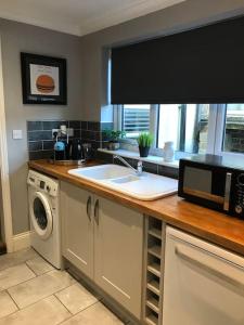 a kitchen with a sink and a microwave at Spacious 3 bed house near beach! in Lowestoft