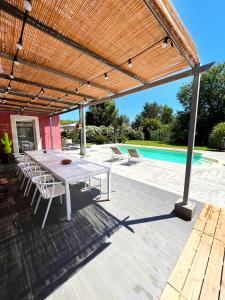 um pátio com uma mesa e cadeiras sob uma pérgula de madeira em VILLA NOAVA em La Crau