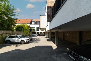 two cars parked in a parking lot next to a building at White Innk city center apartment in Trnava