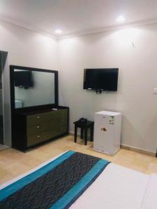 الياسمين للشقق المفروشة في جدة: غرفة نوم مع تلفزيون وخزانة مع مرآة