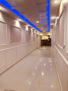un lungo corridoio con pareti bianche e soffitti blu di الياسمين للشقق المفروشة a Gedda