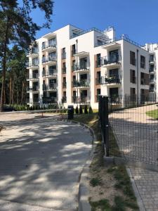 un edificio de apartamentos blanco con una valla delante en Apartament Business&Living No 73 z jacuzzi Nad Zalewem w Cedzynie i miejscem parkingowym w hali garażowej, en Cedzyna