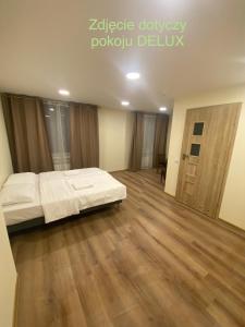 1 dormitorio con 1 cama y suelo de madera en Leśna Polana, en Sękocin Stary
