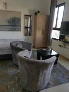 ein Wohnzimmer mit 2 Stühlen, einem Tisch und einem Bett in der Unterkunft נופש מול הכנרת Vacation in front of the Sea Galilee in Tiberias