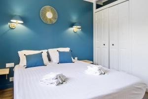 a blue bedroom with a white bed with towels on it at Villa de la Côte - Welkeys in Labenne