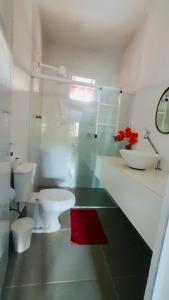 y baño con aseo, lavabo y alfombra roja. en Casa em condomínio a 500m da praia de Pernambuco ideal para família, en Guarujá
