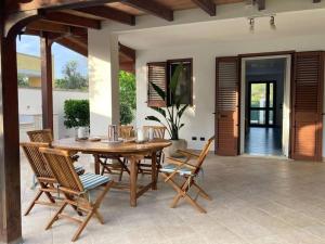 Un patio con una mesa y sillas de madera. en Villa Carolina, en Torre Specchia Ruggeri