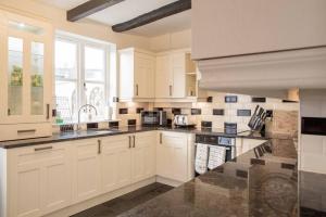 a large kitchen with white cabinets and a sink at Charming 2 Bed House in Tewkesbury Centre in Tewkesbury