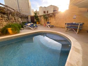 - une piscine sur une terrasse avec une table et des chaises dans l'établissement Gozo Sunset Farmhouse, à Qala