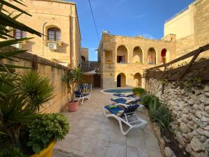 - une terrasse avec des chaises longues et une piscine dans un bâtiment dans l'établissement Gozo Sunset Farmhouse, à Qala