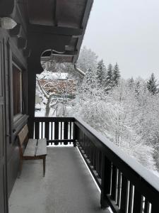 een balkon met een bank en met sneeuw bedekte bomen bij L'appel Chalet in Choex