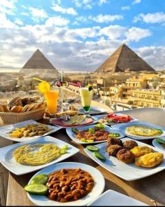 a table with plates of food with pyramids in the background at Toman Pyramids hotel in Cairo