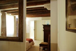 een kamer met een spiegel, een bed en een stoel bij Appartamento Corte Bragadin in Venetië