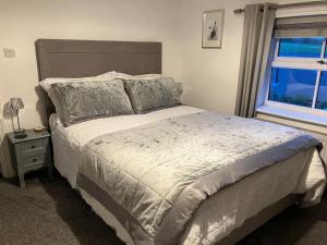 a bedroom with a large bed and a window at Woodbine Cottage-PART OF ALTON COTTAGES in Alton