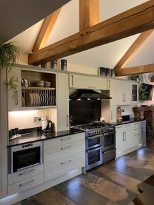 une grande cuisine avec des placards blancs et une cuisinière dans l'établissement Woodbine Cottage-PART OF ALTON COTTAGES, à Alton