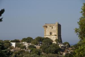 
a tall tower with a clock on it's side at Torre di Scopello in Scopello
