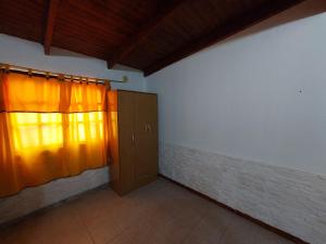 una habitación vacía con una ventana con cortinas naranjas en Alquileres temporarios Anahi en Las Heras