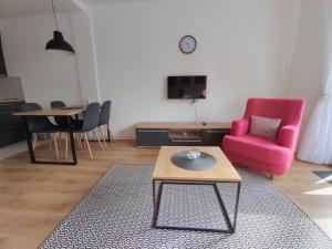 un soggiorno con una sedia rosa e un tavolo di Apartmani Šišarka 1 a Kopaonik