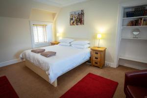 a bedroom with a white bed and a red rug at Edengrove in Aberfeldy