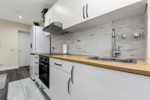 una cocina con armarios blancos y fregadero en 2 Bed Flat Zone 2 Overground Close Central London, en Londres