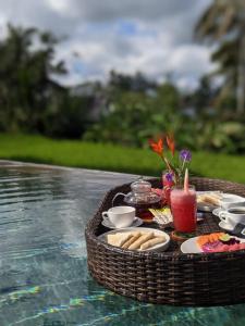 a picnic table with food and drinks on a table in the water at Umah Tirta in Ubud