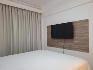 1 dormitorio con 1 cama y TV de pantalla plana en Apartamento Rota do Mar, en Bombinhas