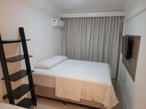 Dormitorio pequeño con cama y TV en Apartamento Rota do Mar, en Bombinhas