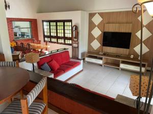 a living room with a red couch and a flat screen tv at Casa Barlavento com Piscina e Praia em Angra - RJ in Angra dos Reis
