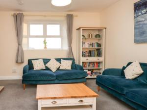 a living room with two blue couches and a book shelf at Garden Cottage in Alnwick