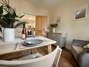 uma cozinha com uma mesa com um prato e copos de vinho em Garden Cottage em Alnwick