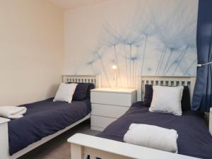 a bedroom with two beds and a table with a lamp at Garden Cottage in Alnwick