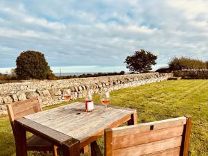 a wooden table with two glasses of wine on a field at Garden Cottage in Alnwick