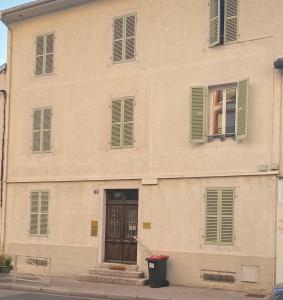 a building with green shuttered windows and a door at T2 meuble in Oyonnax