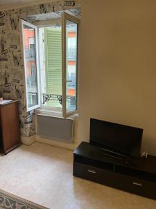 a living room with a tv and a window at T2 meuble in Oyonnax