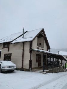 a snow covered house with a car parked in front of it at Palaga Bukovel in Bukovel