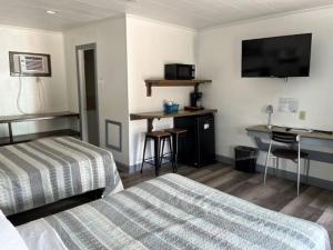 a hotel room with a bed and a desk and a television at Swell Motel in Buxton