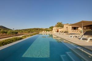 a large swimming pool with chairs and a building at Hotel Rural Es Riquers in Porreres