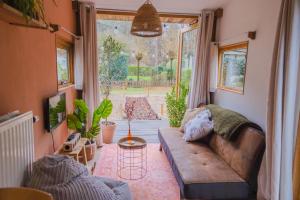 a living room with a couch and a large window at Tiny House Hilver - uniek en sfeervol huisje middenin het bos in Diessen