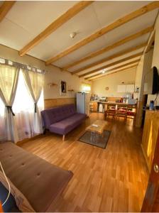 sala de estar con sofá púrpura y cocina en Cabañas Rukapillán Región de la Araucanía, en Villarrica