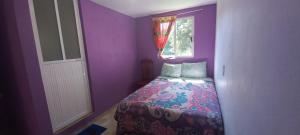 Habitación púrpura con cama y ventana en Hotel Bosques en Zacatlán