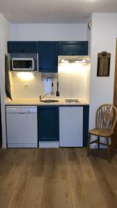 a kitchen with blue cabinets and a sink and a chair at Studio - Le D2 du Grand Tetras in Samoëns
